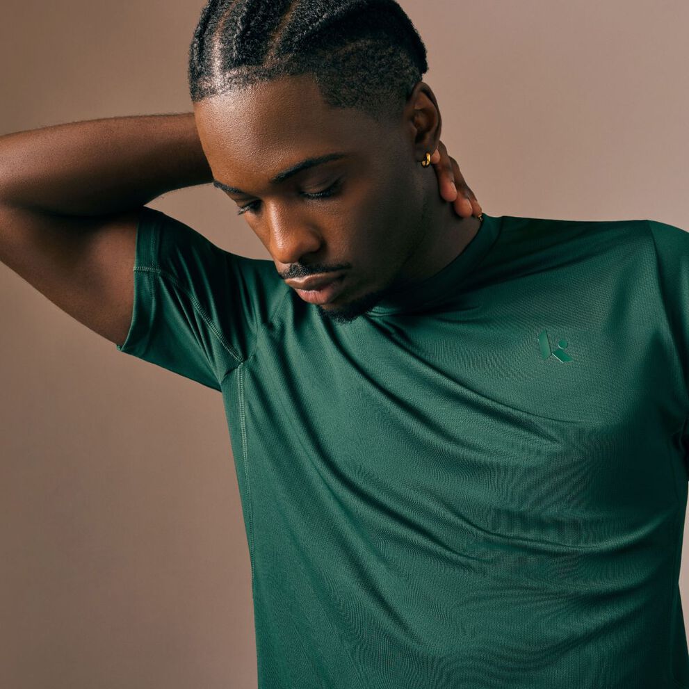 Young man in a green shirt looking at the ground.