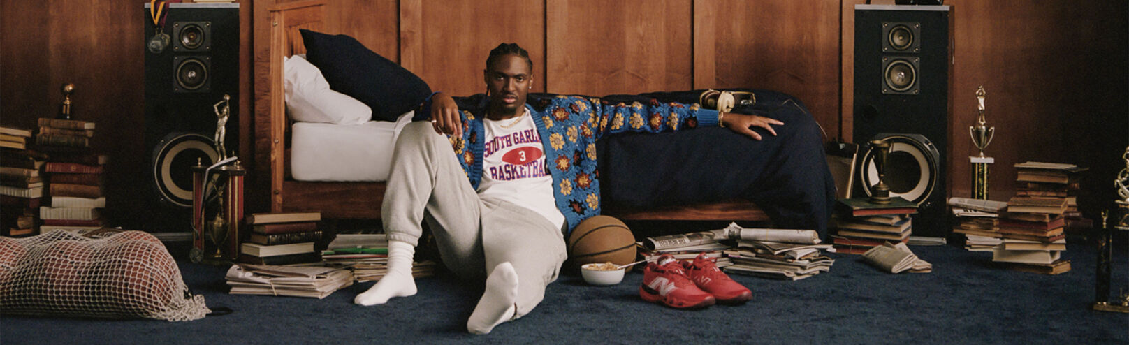 Tyrese Maxey sitting on a bedroom floor with a basketball and Hesi Lows