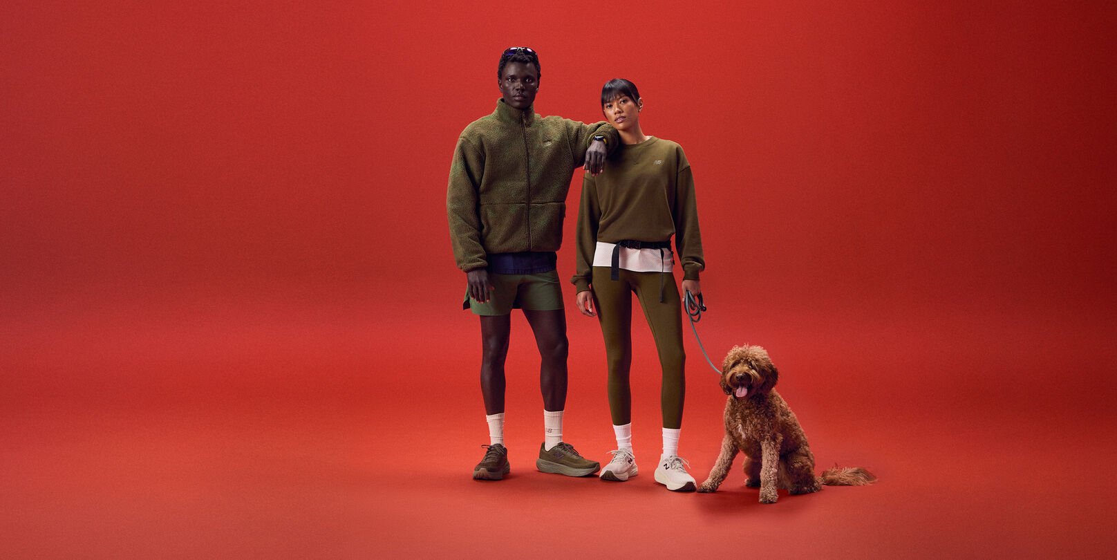 Young couple standing on a red background with a dog.