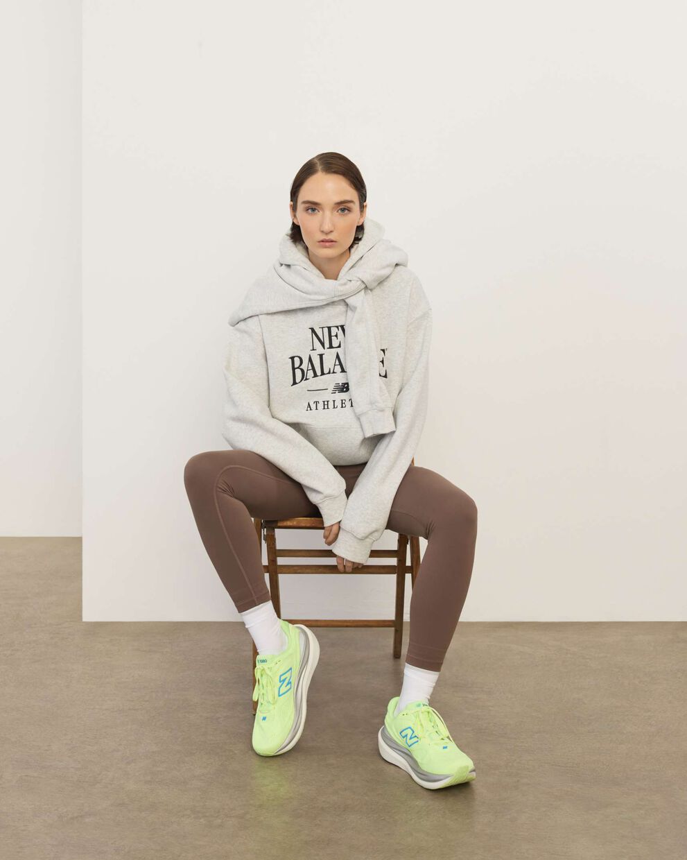 A woman sitting in a chair in front a white wall.