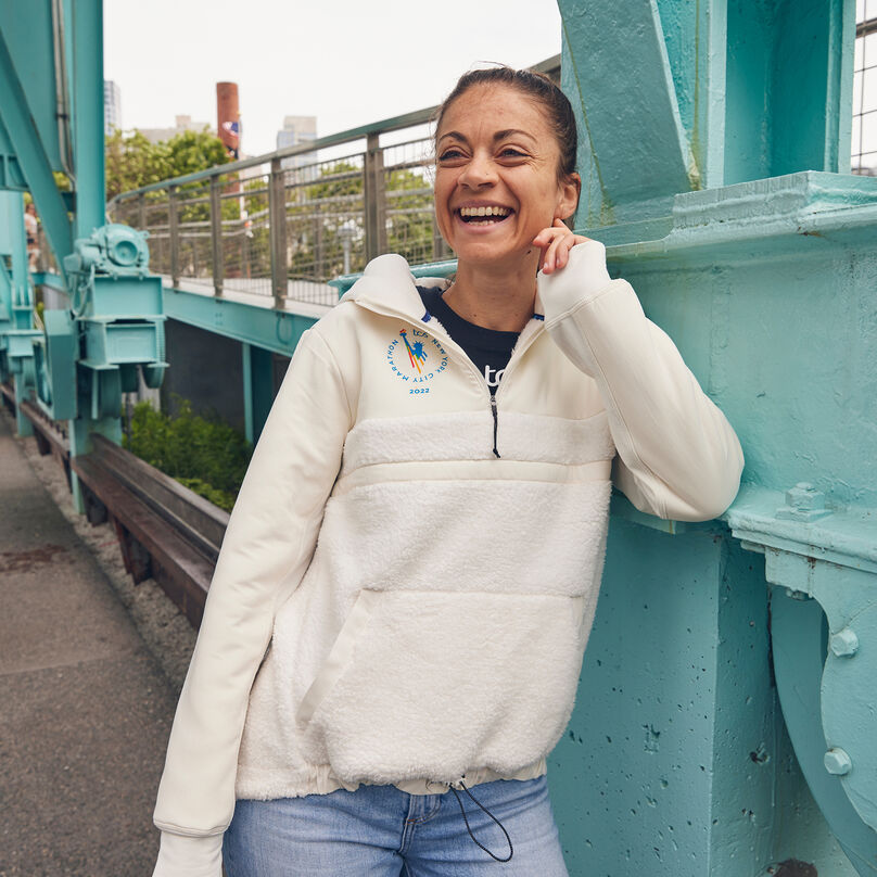 Woman leaning against a bridge rail laughing.