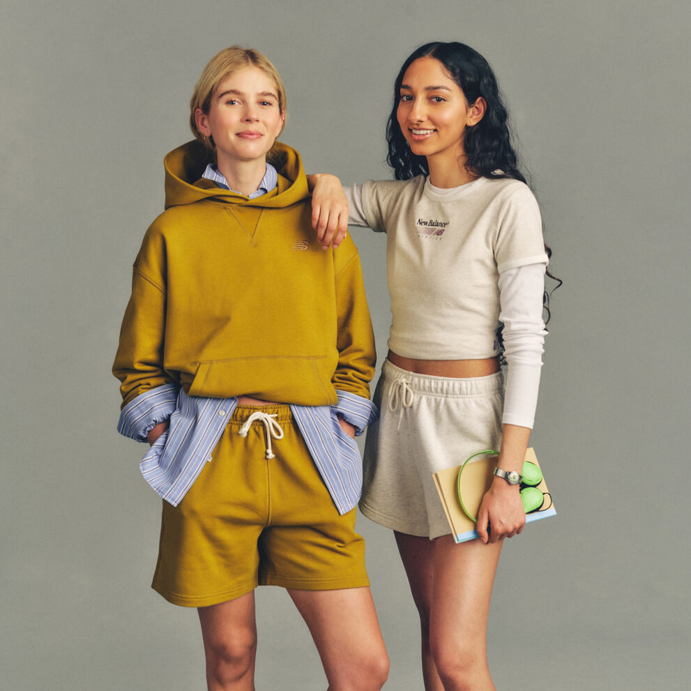 Imagen de estudio de dos personas situadas sobre un fondo gris claro sencillo, vestidas con ropa deportiva informal.