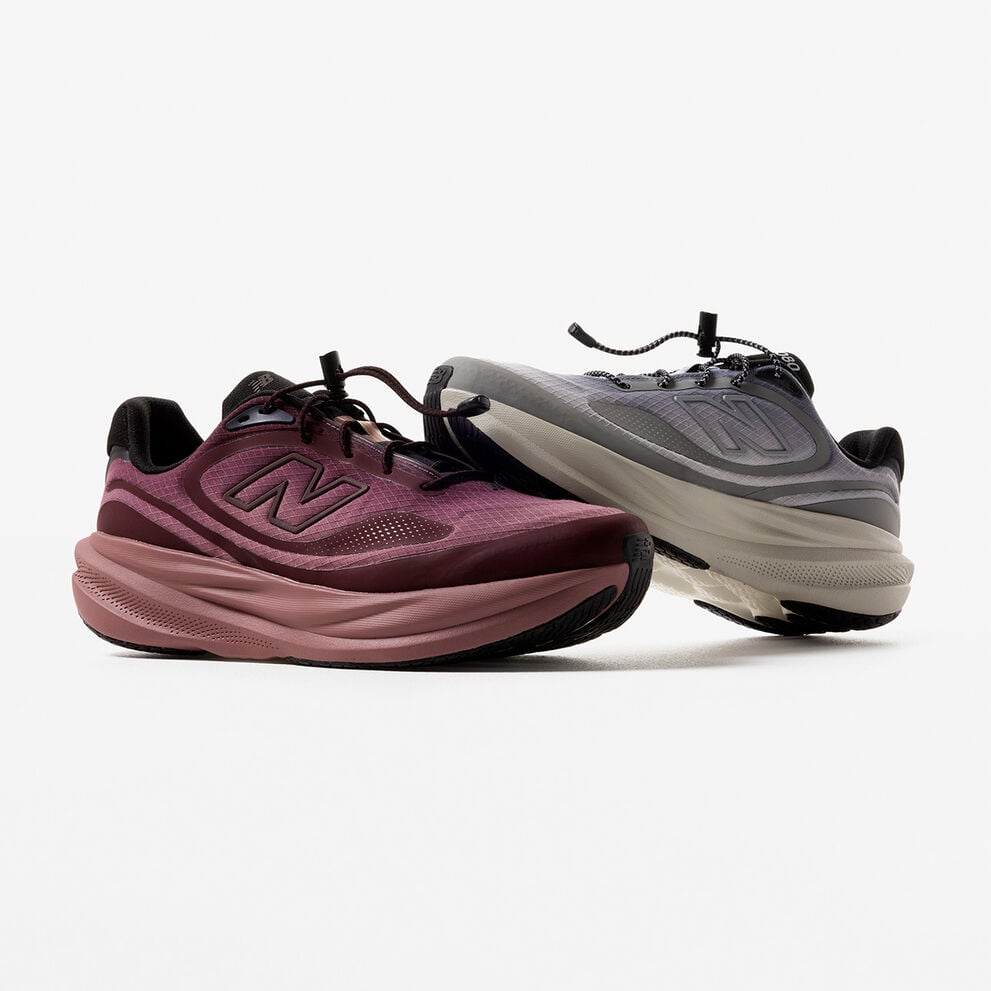 A plum colored and grey colored shoe stacked on each other against a grey studio backdrop