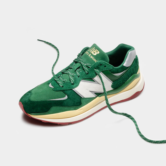 Single green 57/40 shoe with laces out shot at an angle against grey studio background