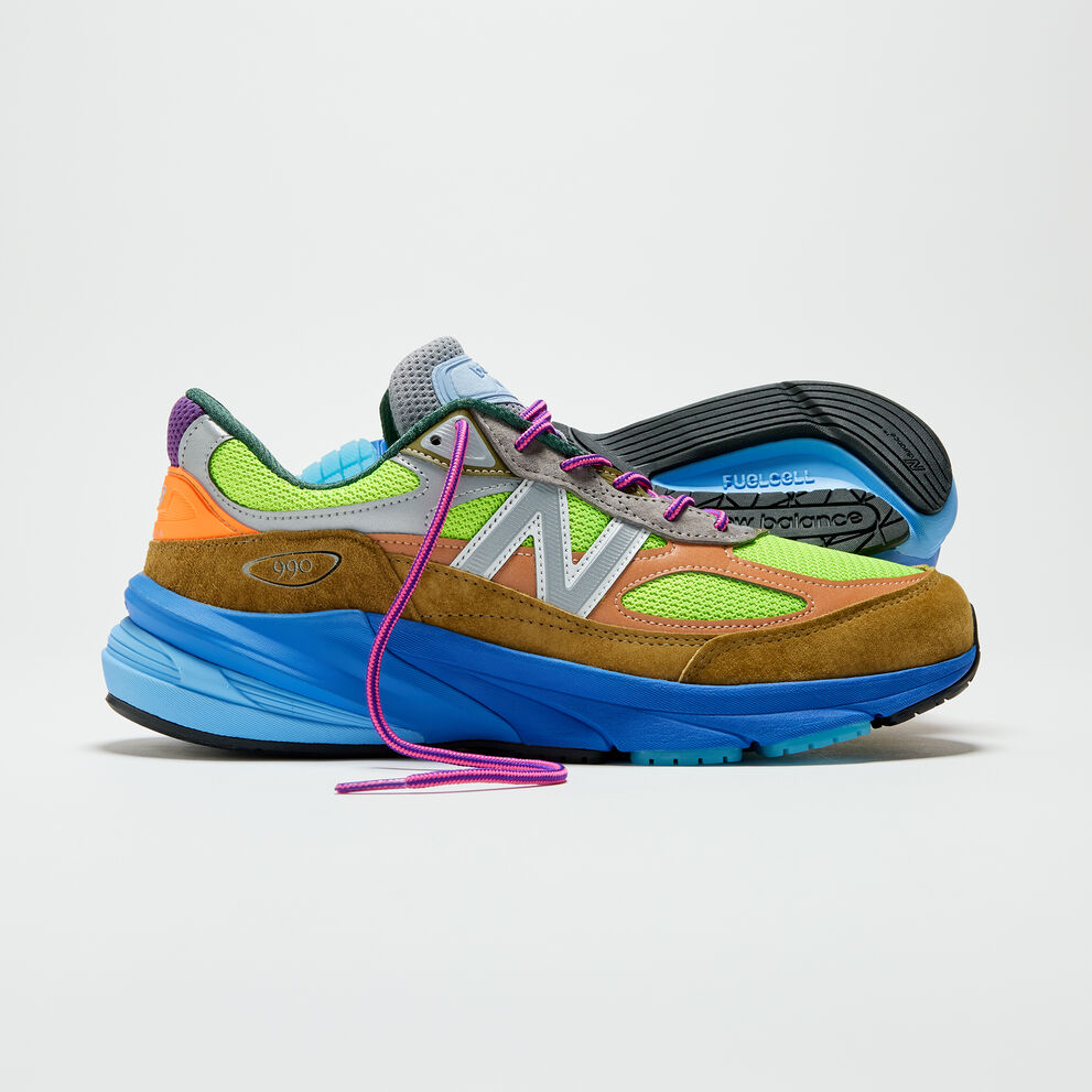 Multi-colored shoes sitting on a grey background with the pink laces untied. 
