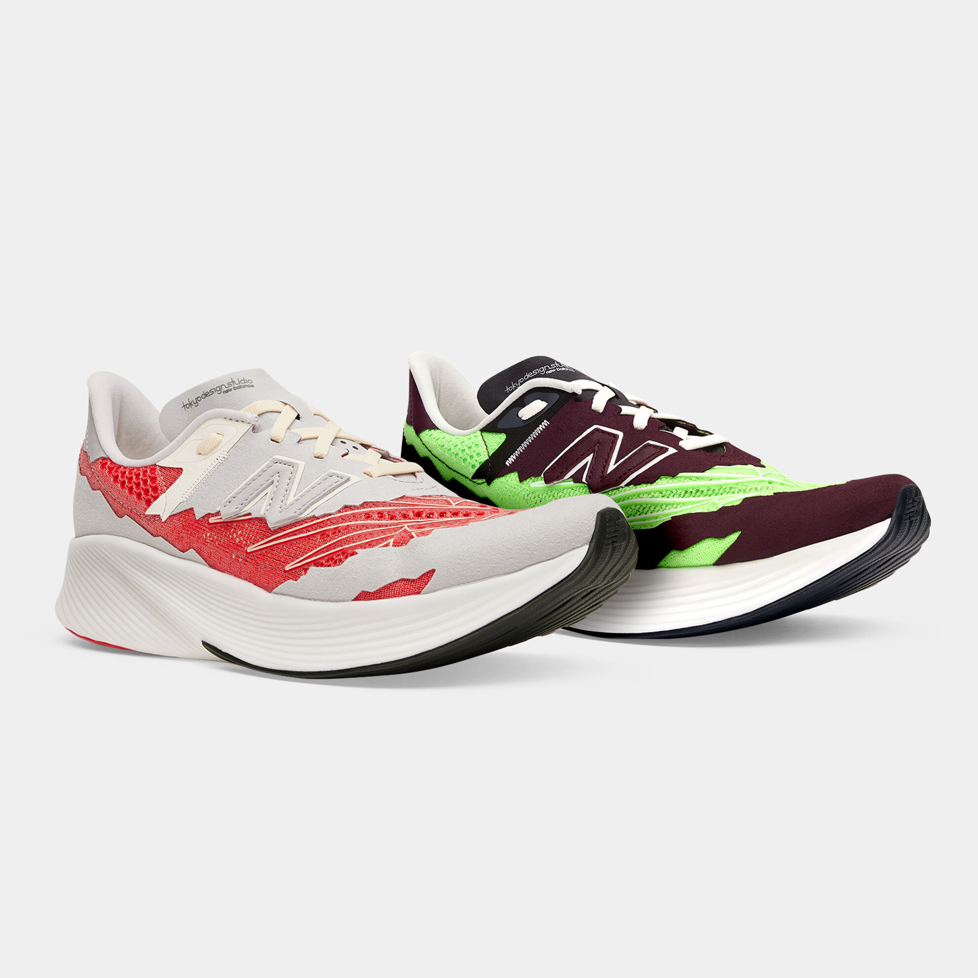 ¾ front angle of two NB Stone Island Tokyo Design Studio FuelCell RC Elite running shoes sitting on a light grey background. One is light grey with red accents and the other is dark reddish brown with lime-green accents