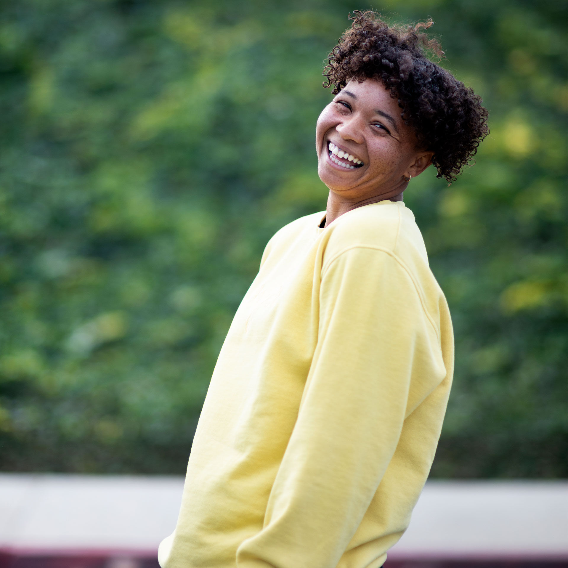 Skateboarder Samarria Brevard smiling in a white and yellow hoodie
