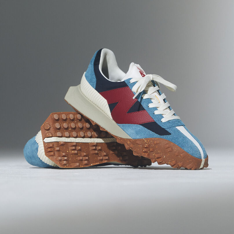 Pair of blue and red shoes propped on top of each other on a grey background.