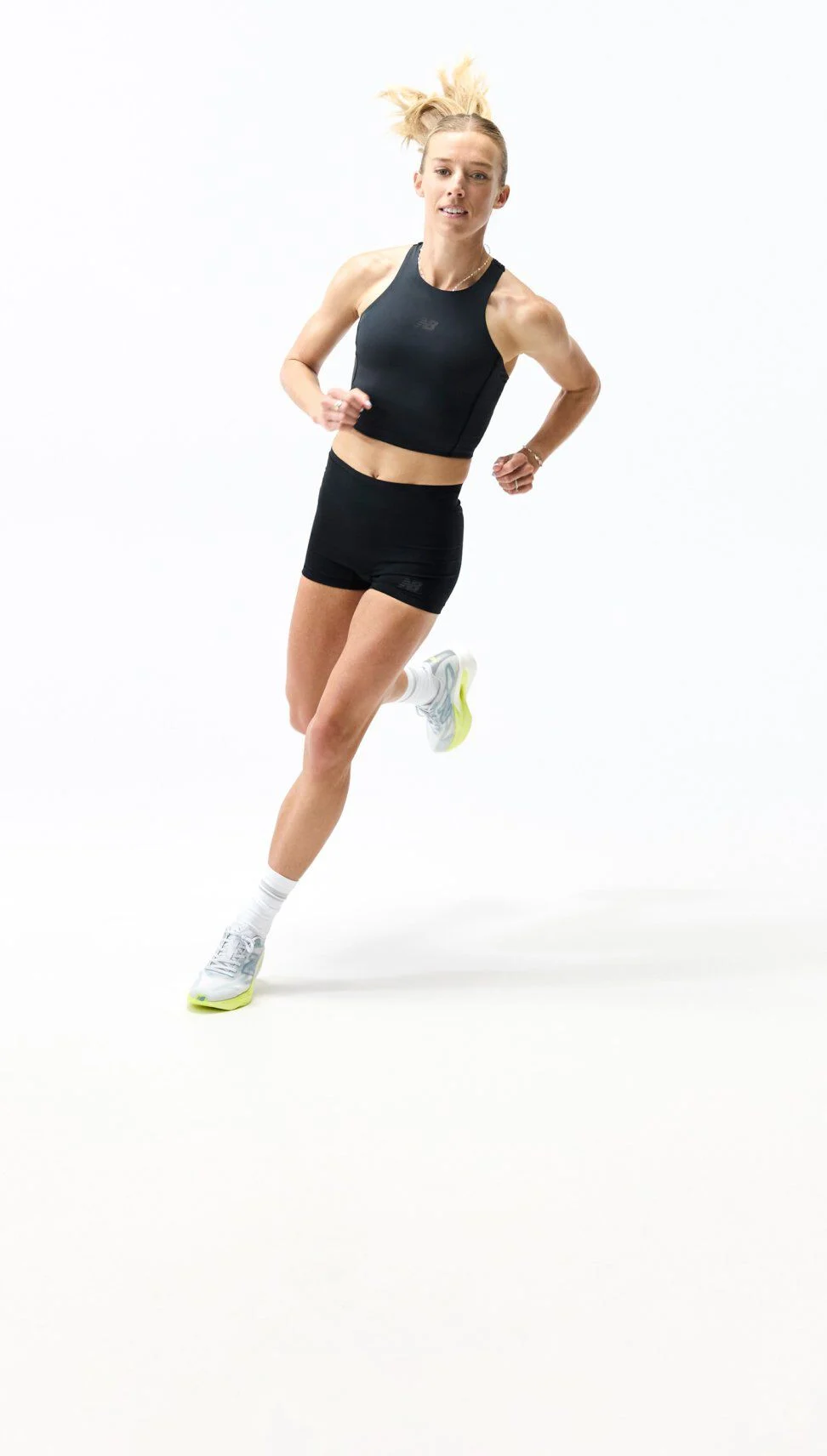 Person running in a studio wearing a black athletic outfit and light gray New Balance running shoes with lime-green soles, shown alongside a close-up of the shoe&rsquo;s cushioned midsole design.
