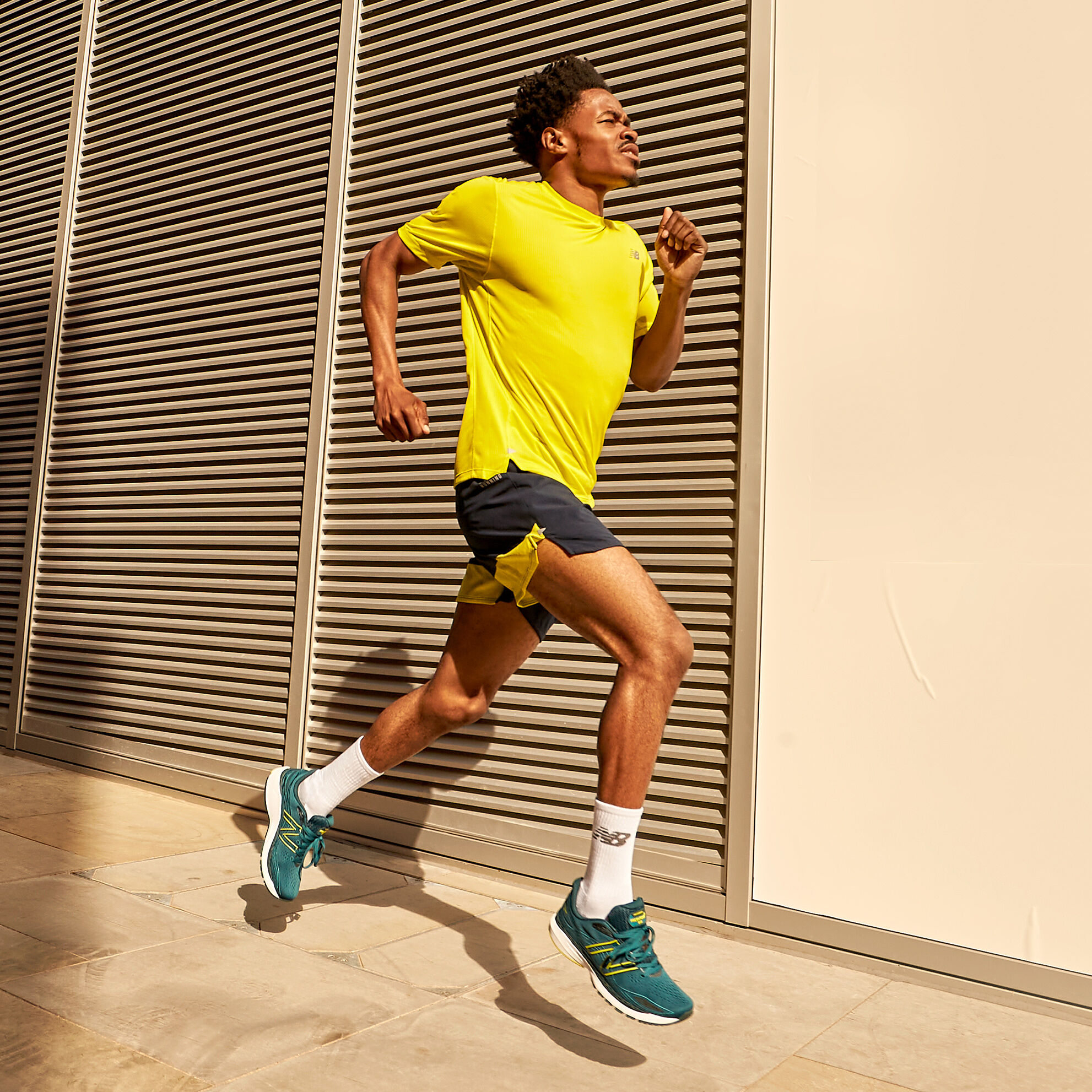 Male runner wearing a yellow shirt, black shorts and the dark green Fresh Foam X 860v12 shoes