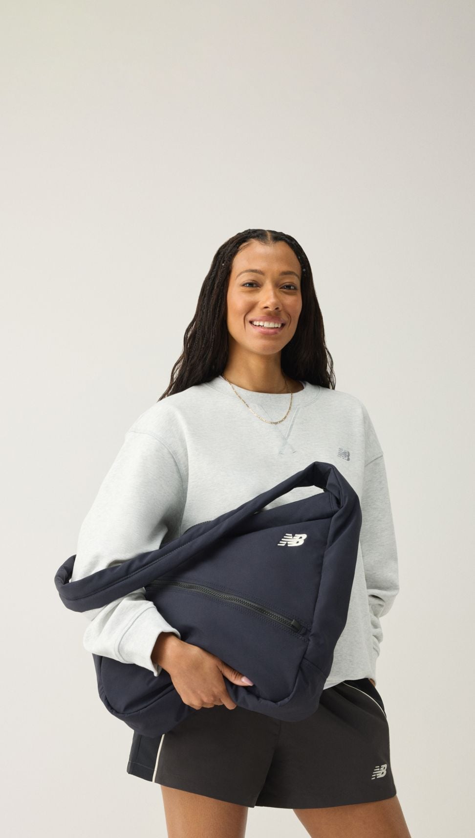 Una mujer que mira al espectador mientras sostiene una mochila azul marino.