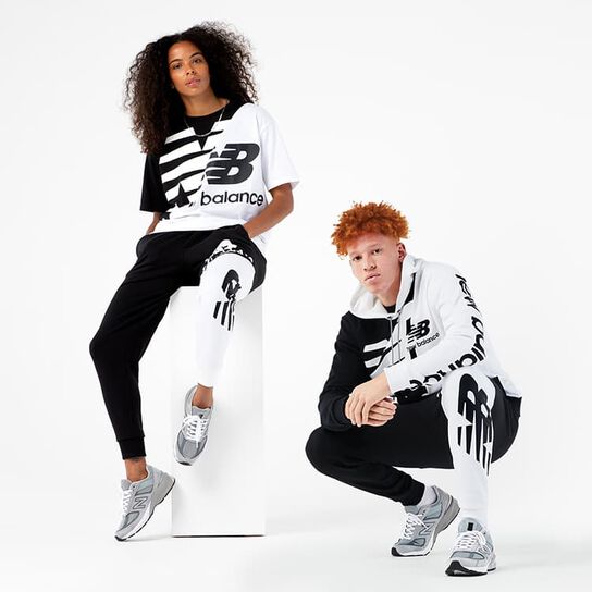 Woman and man in a casual pose wearing black and white casual clothes: tee, sweatshirt and sweatpants. 