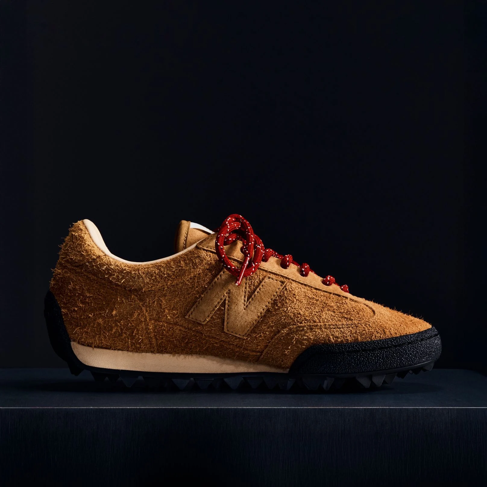 A brown suede Gator Run shoe on a black background.