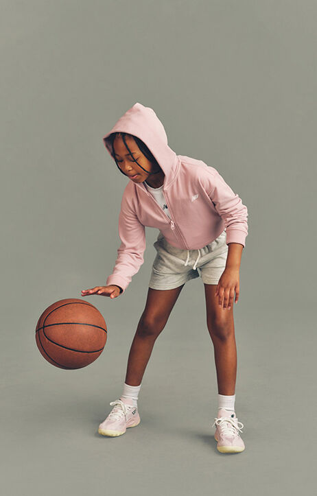 Kid playing with a basketball against a grey studio background.