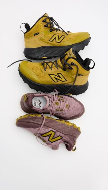 Yellow boots and red trail shoes on the ground all stacked on top of each other 