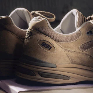 Un par de zapatillas New Balance Made in UK en un estudio de color beige.