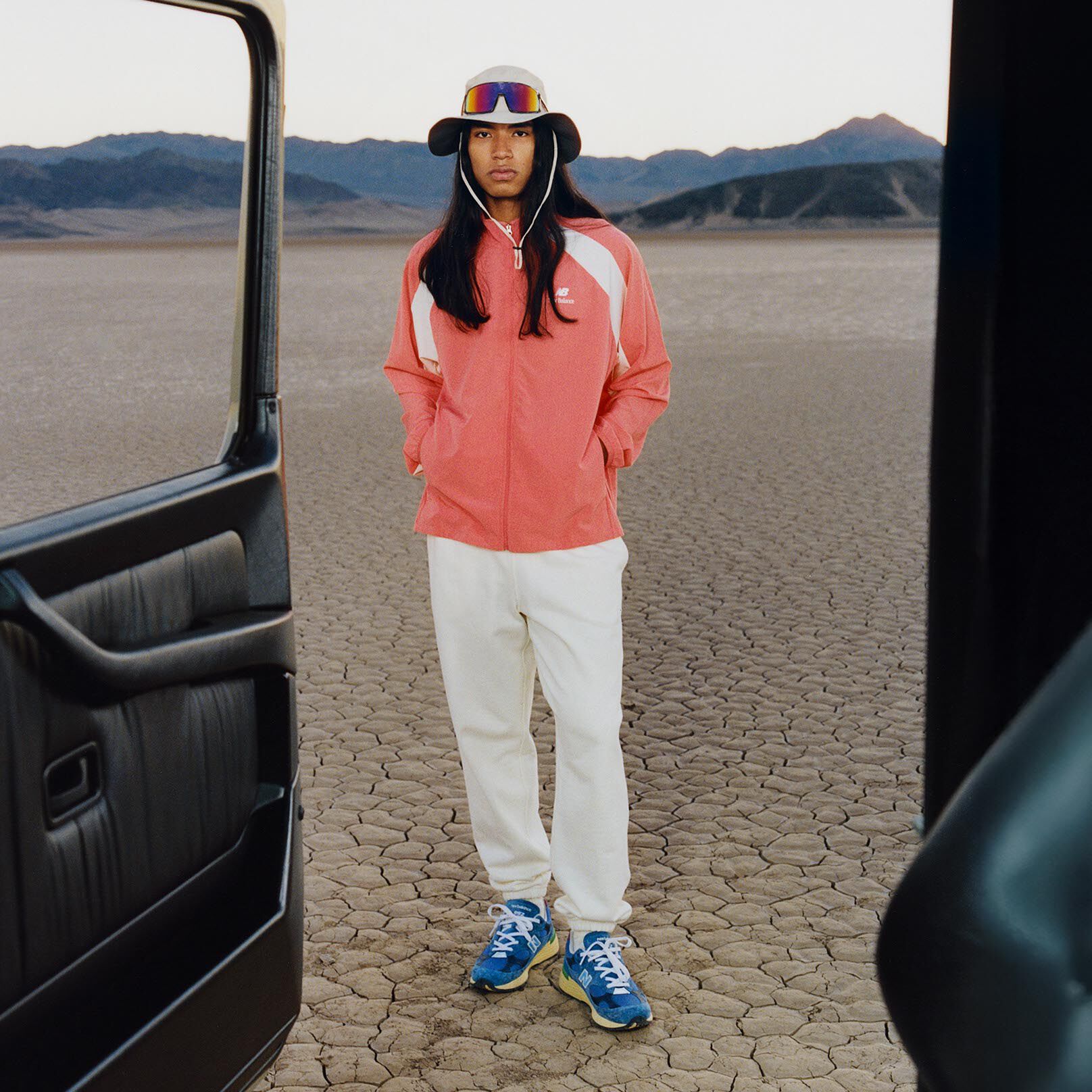 Man wearing a bucket hat and an orange jacket with his hands in his jacket pockets. 