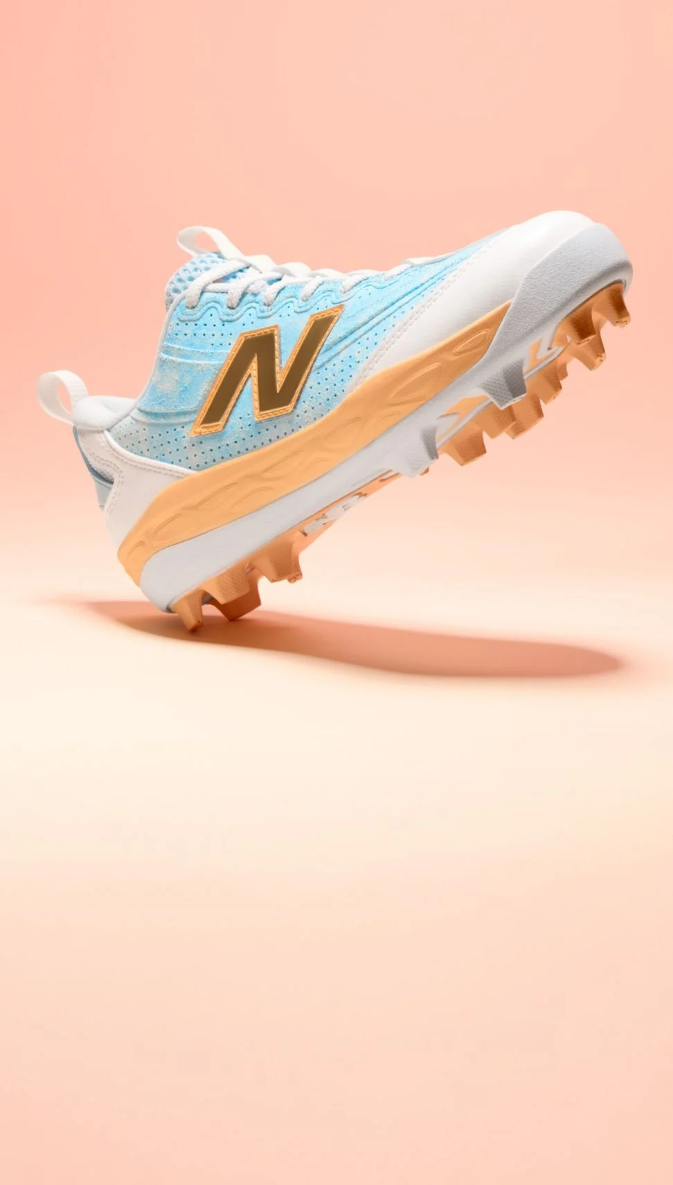 Side view of a single baseball cleat on a light pink gradient background.