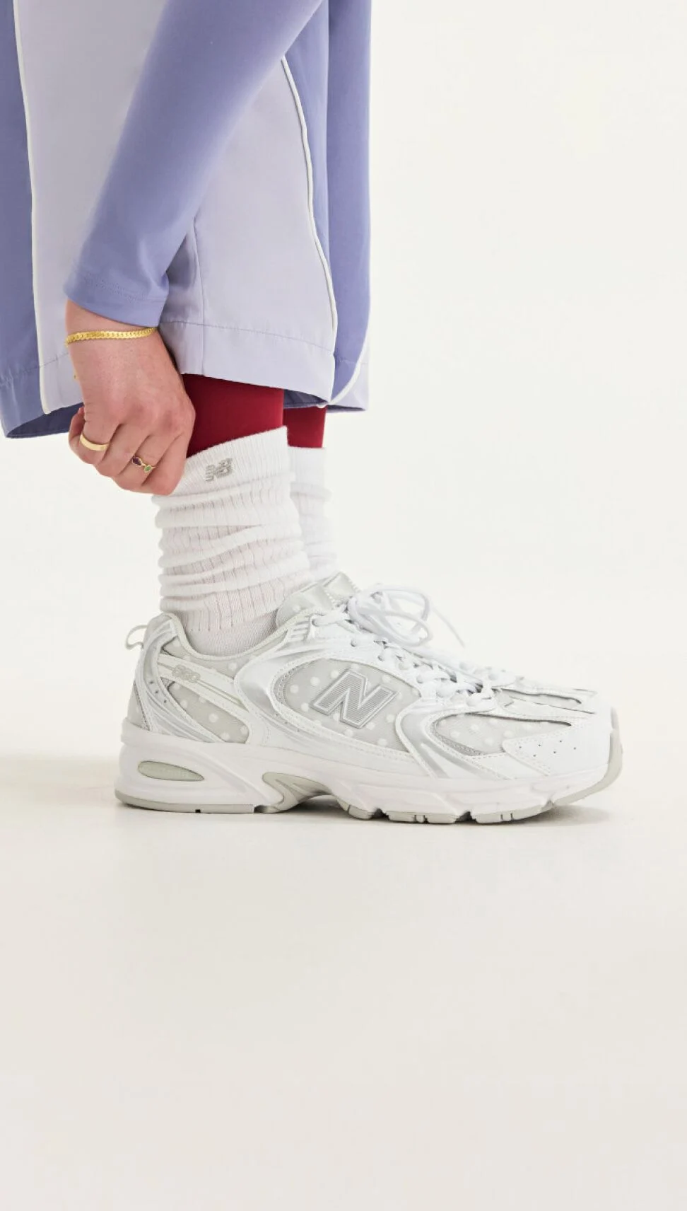 Side view of someone wearing white New Balance sneakers. 