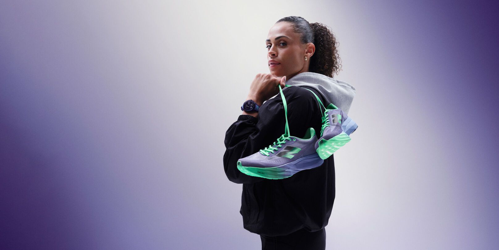 Sydney McLaughlin-Levrone holding a pair of shoes over her shoulder and looking towards the viewer.