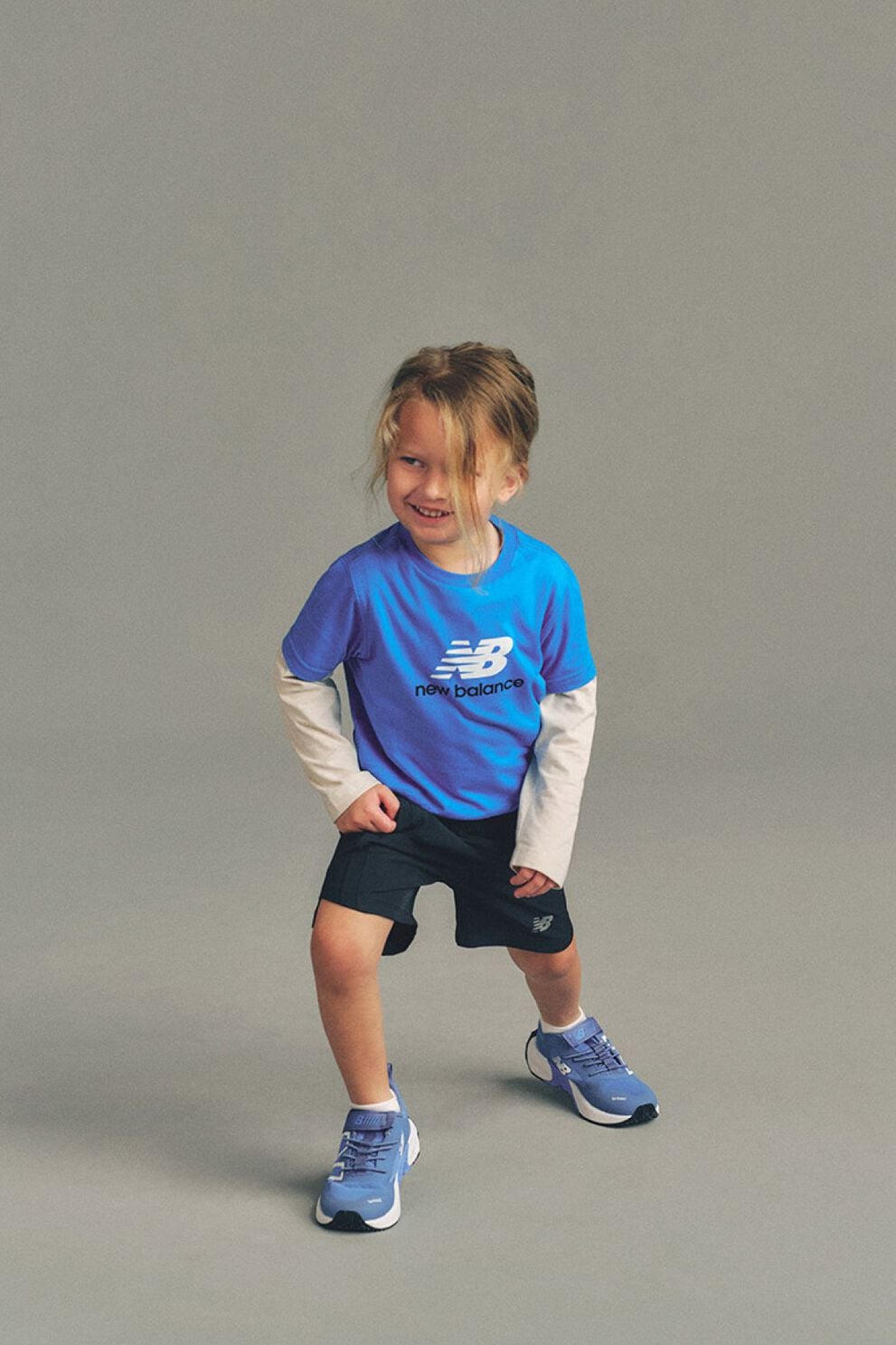 Kid stretching against a grey studio background.