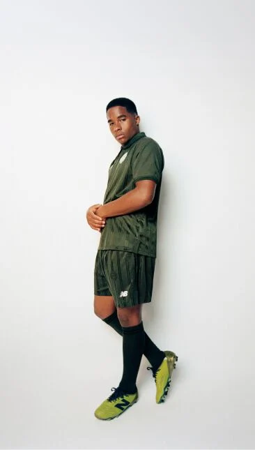 Endrick leaning against a wall wearing a green soccer uniform with his arms together
