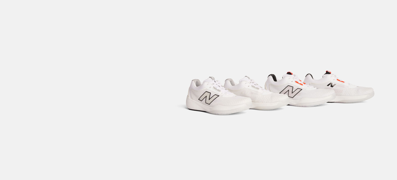 Men's and women's all white tennis shoes sitting on a grey background. 