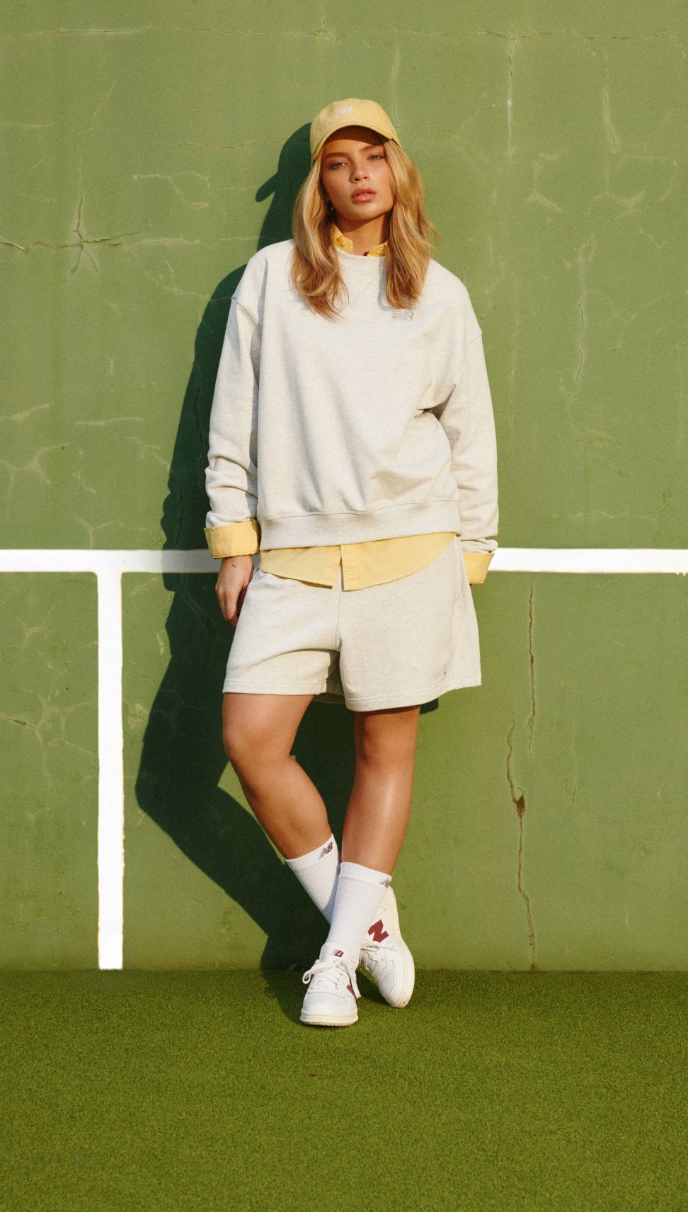 Gabriely standing in a tennis court wearing New Balance T500 shoes. 