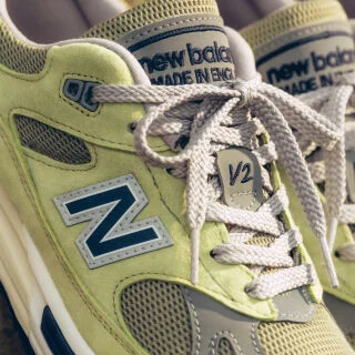 A pair of&nbsp;New Balance Made in UK sneakers in a beige studio environment.