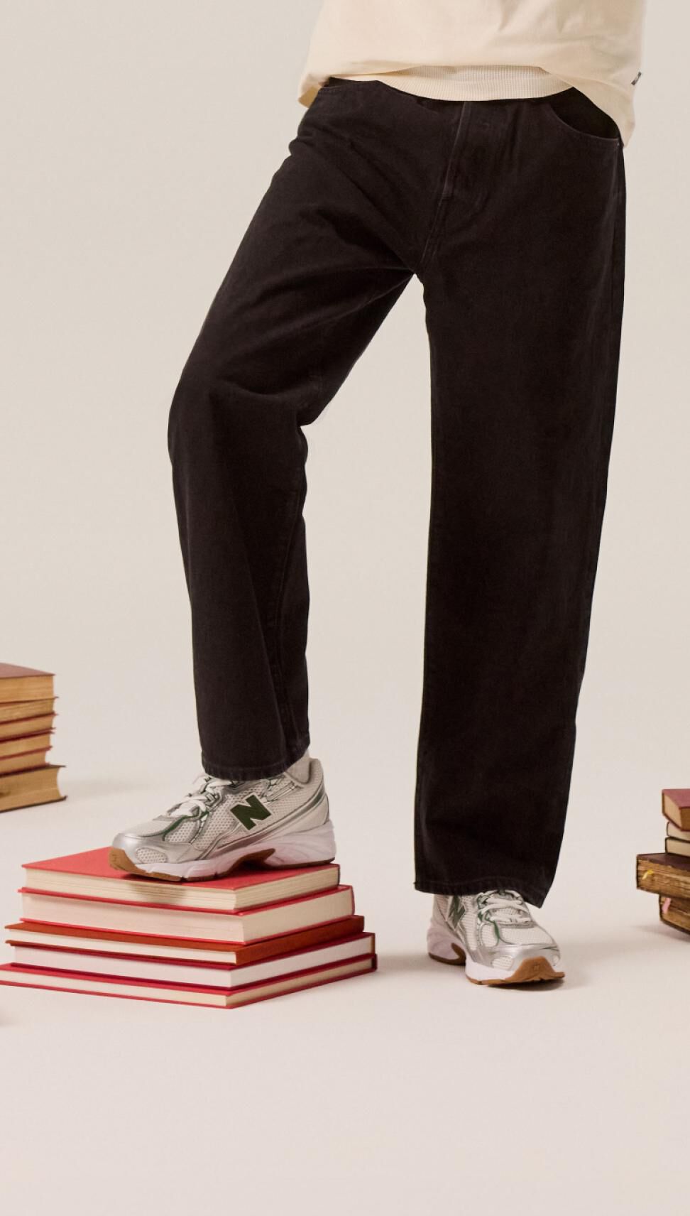 Student in black pants propping their foot up on a pile of books. 