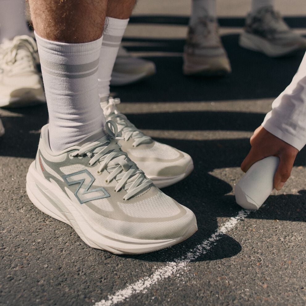 Close-up of someone wearing New Balance running shoes on a sidewalk. 