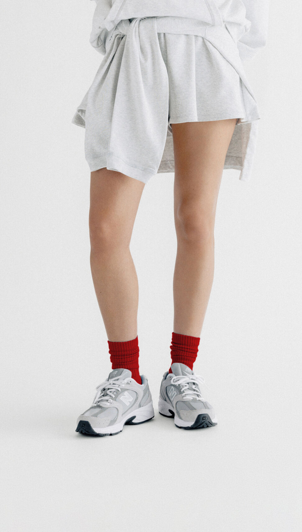 Woman wearing black tights and grey running shoes on a grey background.