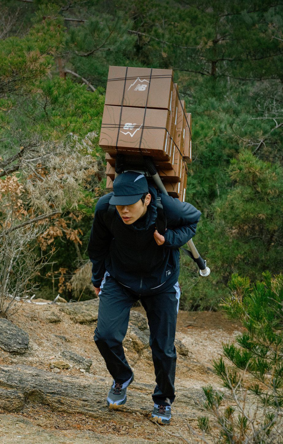 Close-up of someone standing on large rocks while wearing trail running shoes with mesh uppers and tan rubber outsoles.