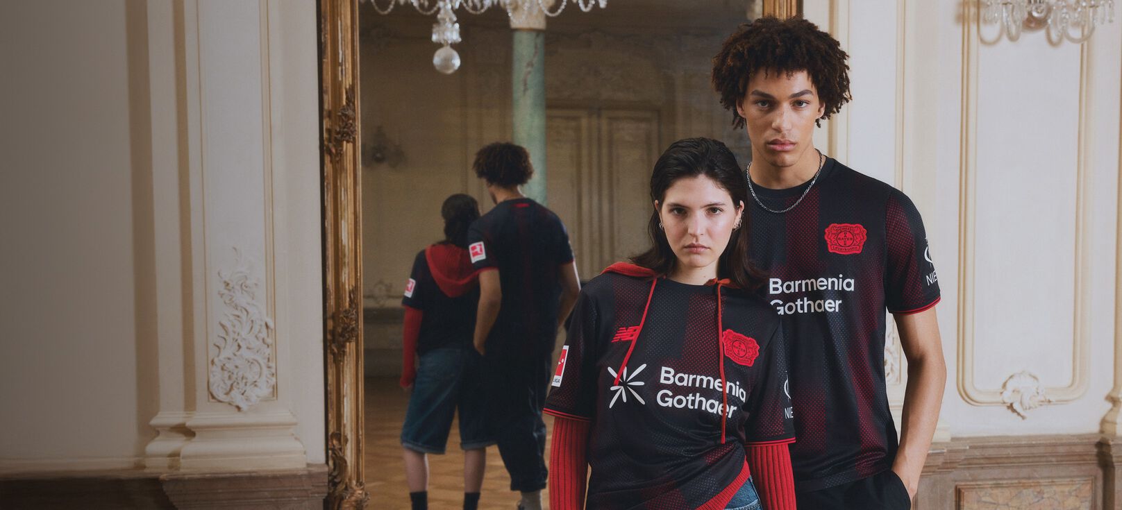Young couple wearing a black soccer jersey in front of a mirror.  