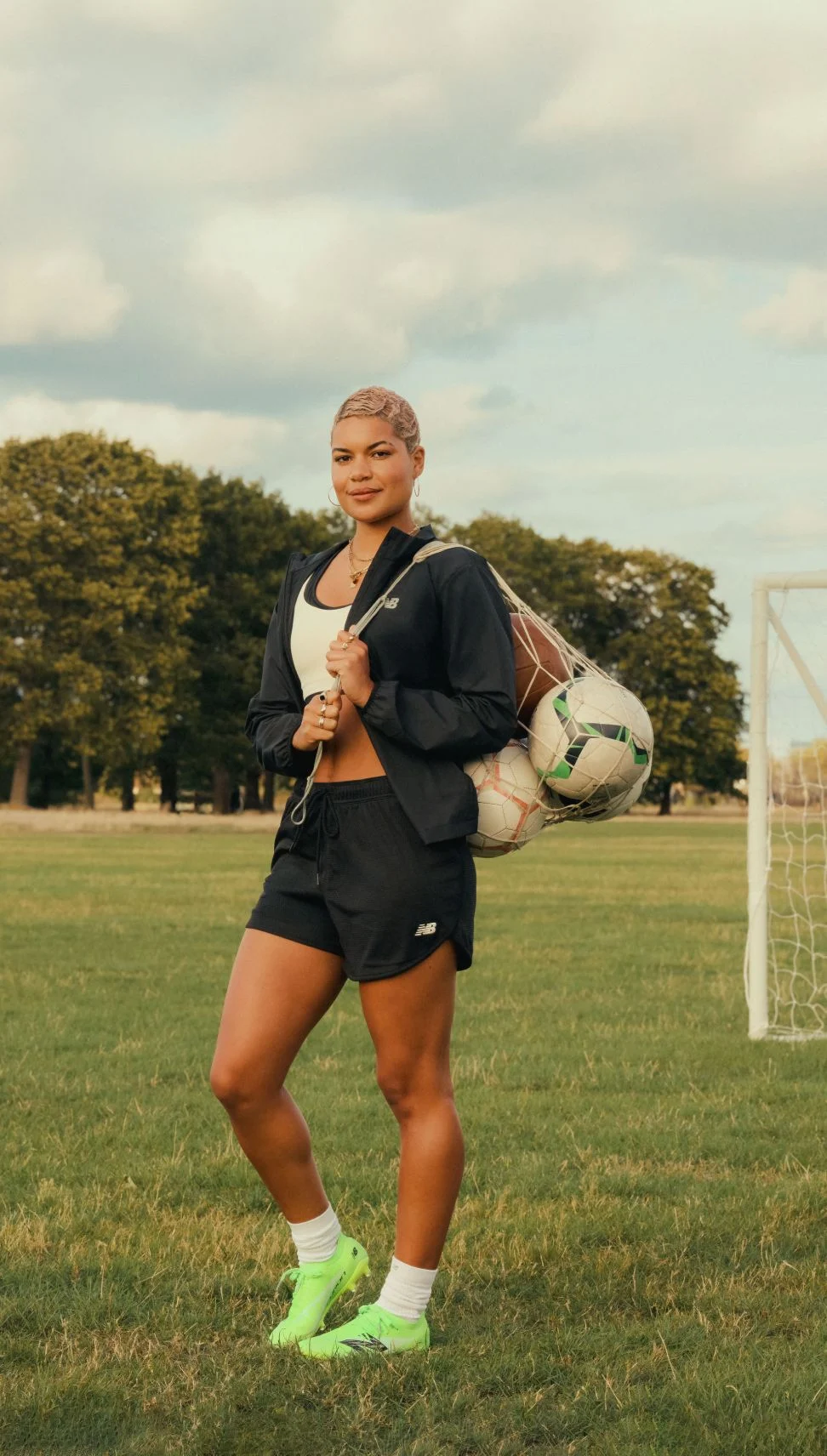 Female soccer player wearing black shorts holding a bag of soccer balls.	