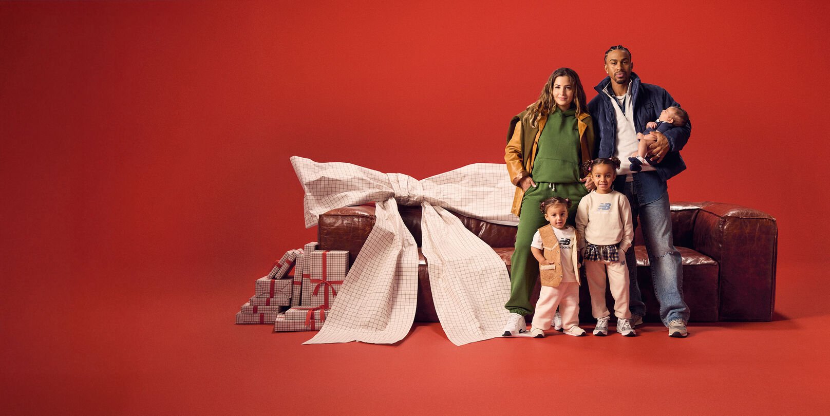 Family gathered around a red couch on a red background.