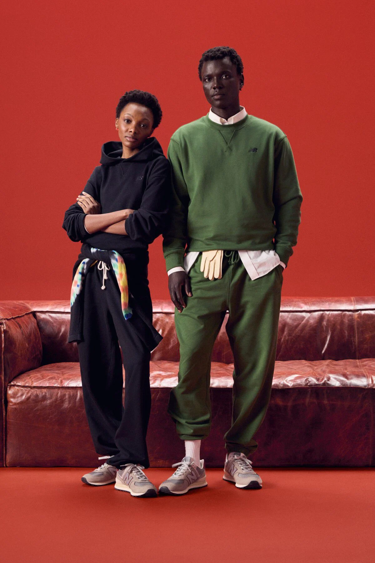Young couple wearing same color outfits standing in front of a red couch.