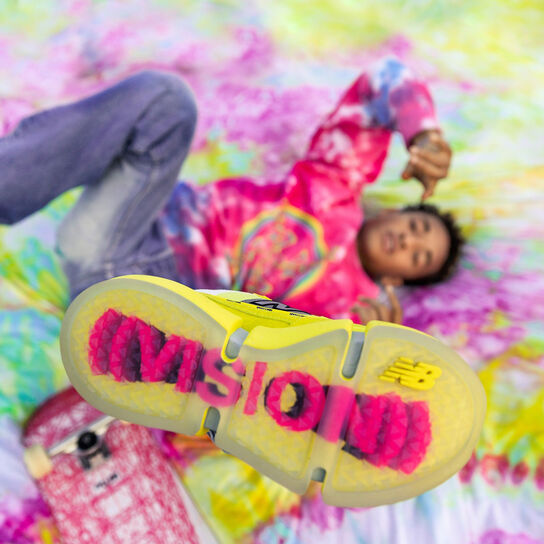 Jaden laying on a tie dye blanket with his left foot in the air showing the bottom of the shoe.