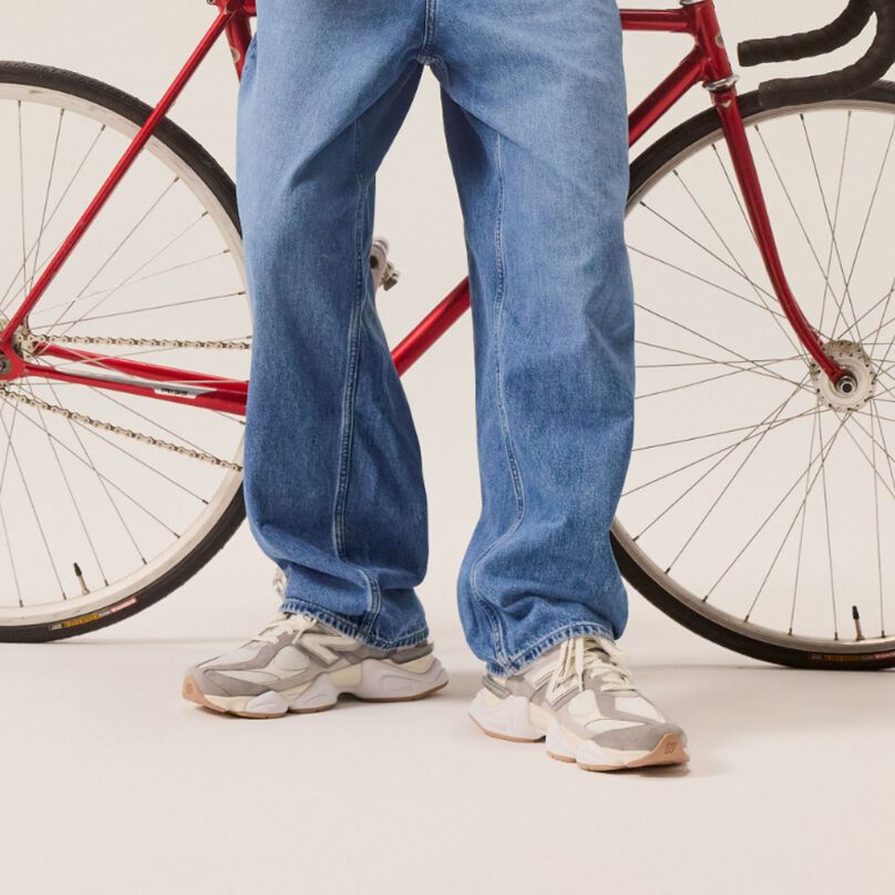 Young man in jeans standing in front of a bike. 