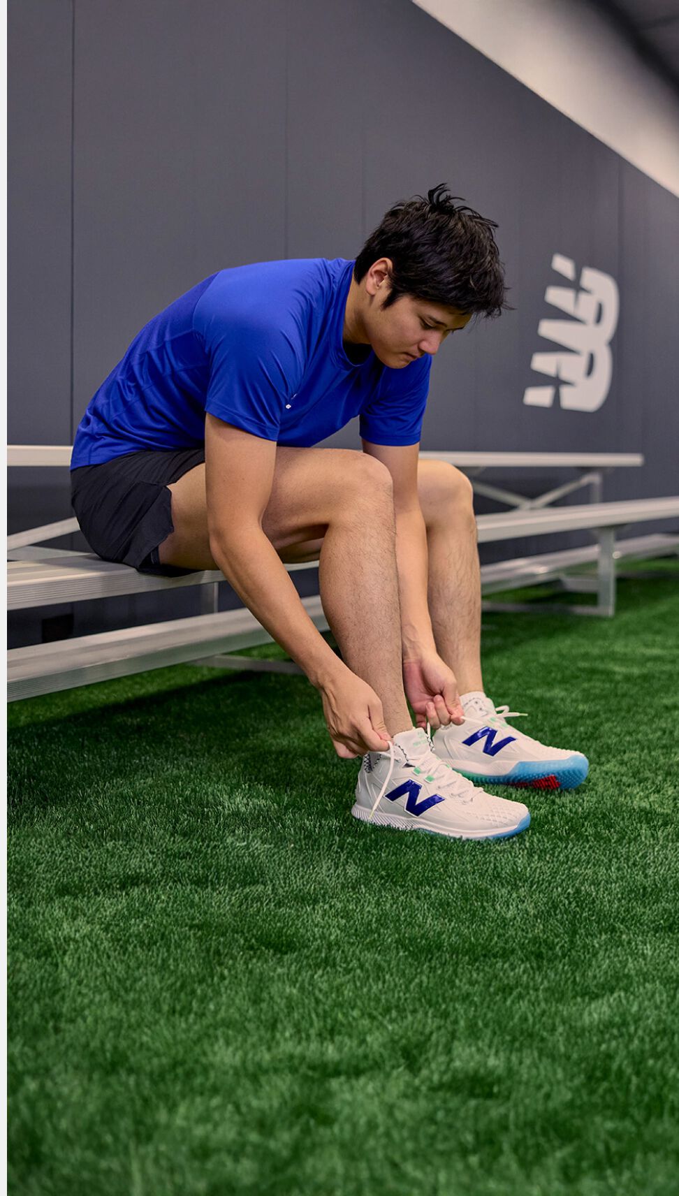 Shohei Ohtani in a training facility tying his shoes. 