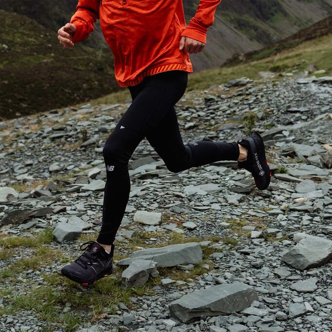 Man in black tights running on rocky trail