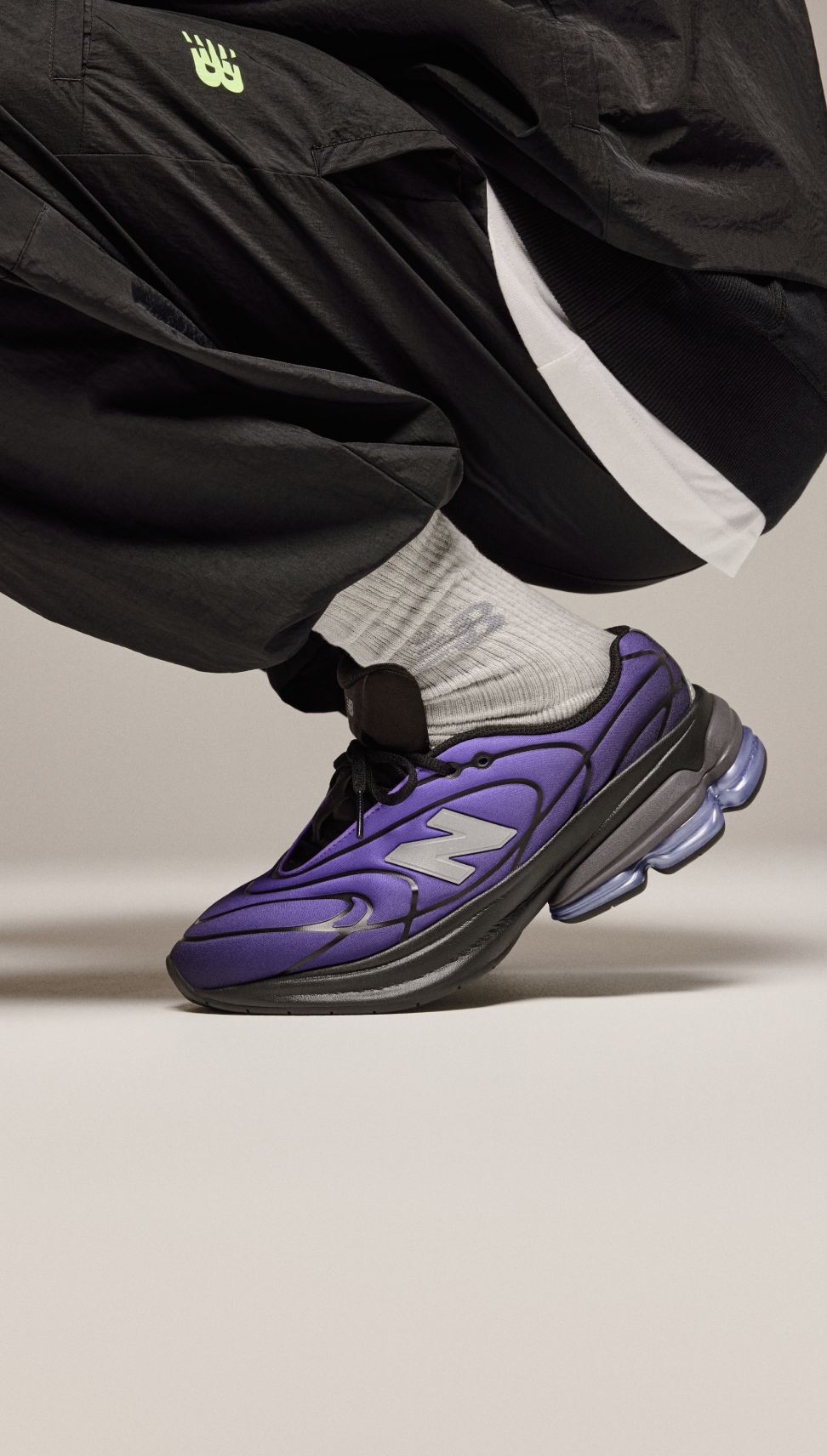 Knee-down of a man wearing purple shoes on a beige background. 