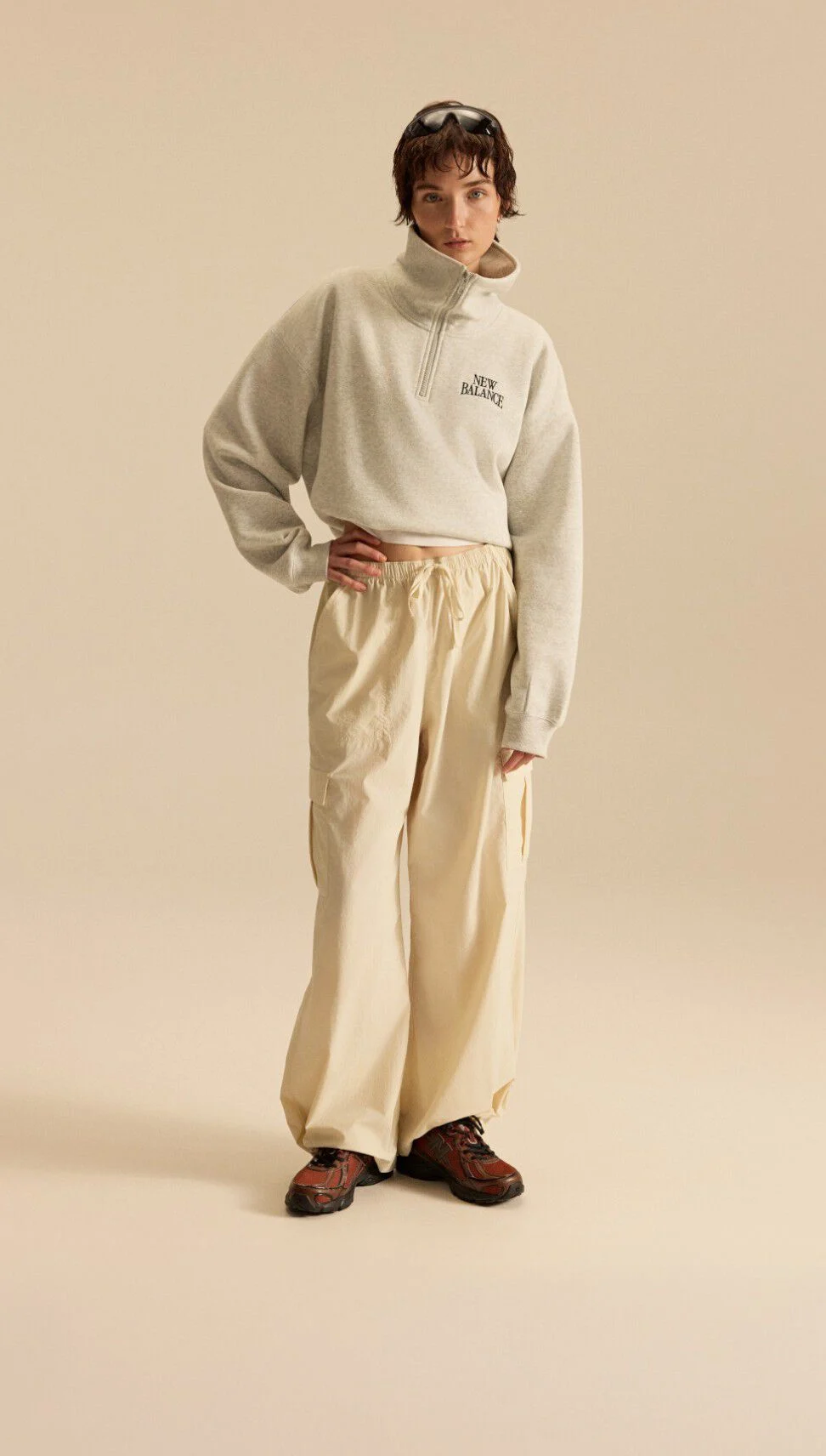 Image of a person in a grey and off white outfit in front of a beige background.