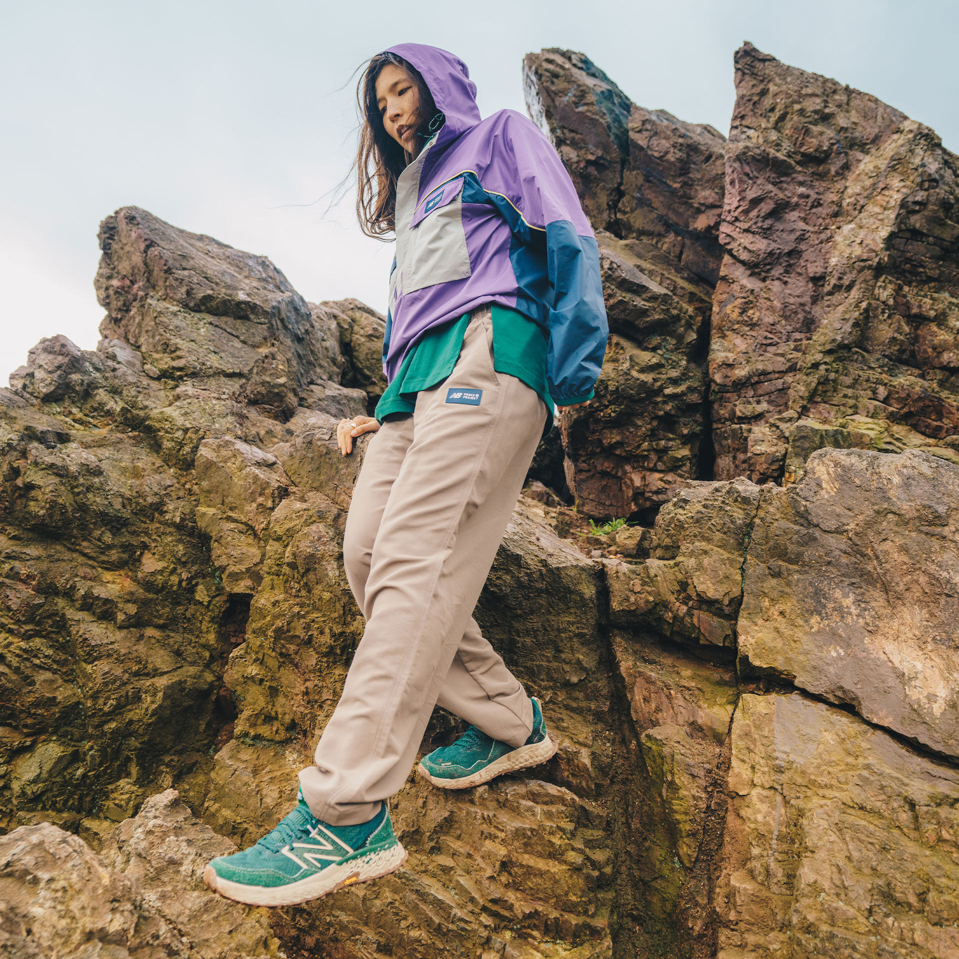 Woman climbing on rocks, wearing Parks Project & NB Apparel and Fresh Foam X Hierro v7 