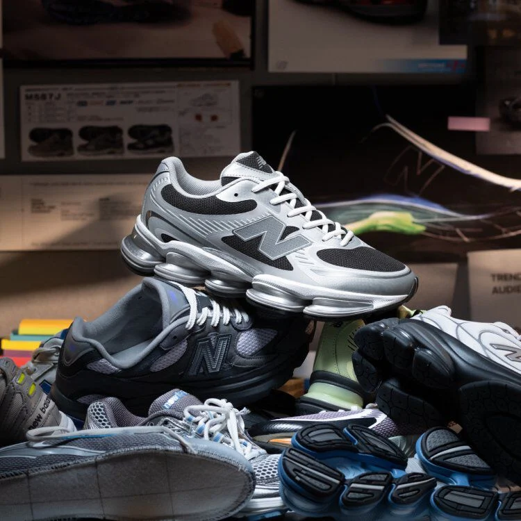 Grey and black shoes sitting on top of a bundle of other shoes.