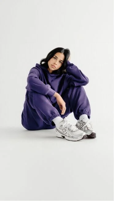 Woman in a purple set sitting down on the ground. 