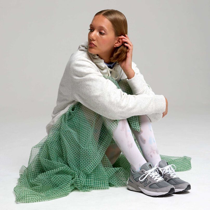 Woman wearing grey 990 sneakers with sweatshirt and green tulle skirt