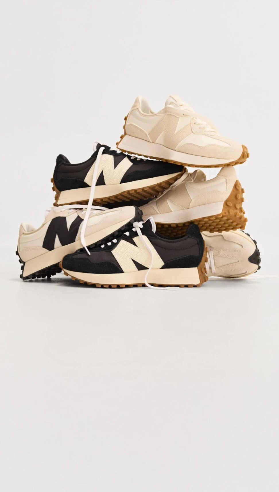Pile of multiple New Balance sneakers on white background.