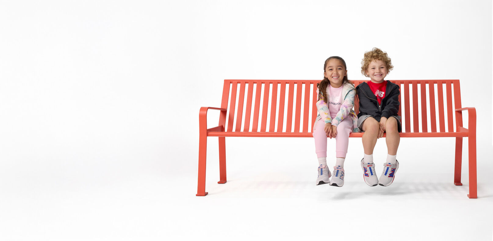 Niño y niña sentados en banco rojo