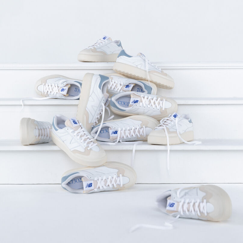 Multiple pairs of white CT302 shoes laying on white stairs